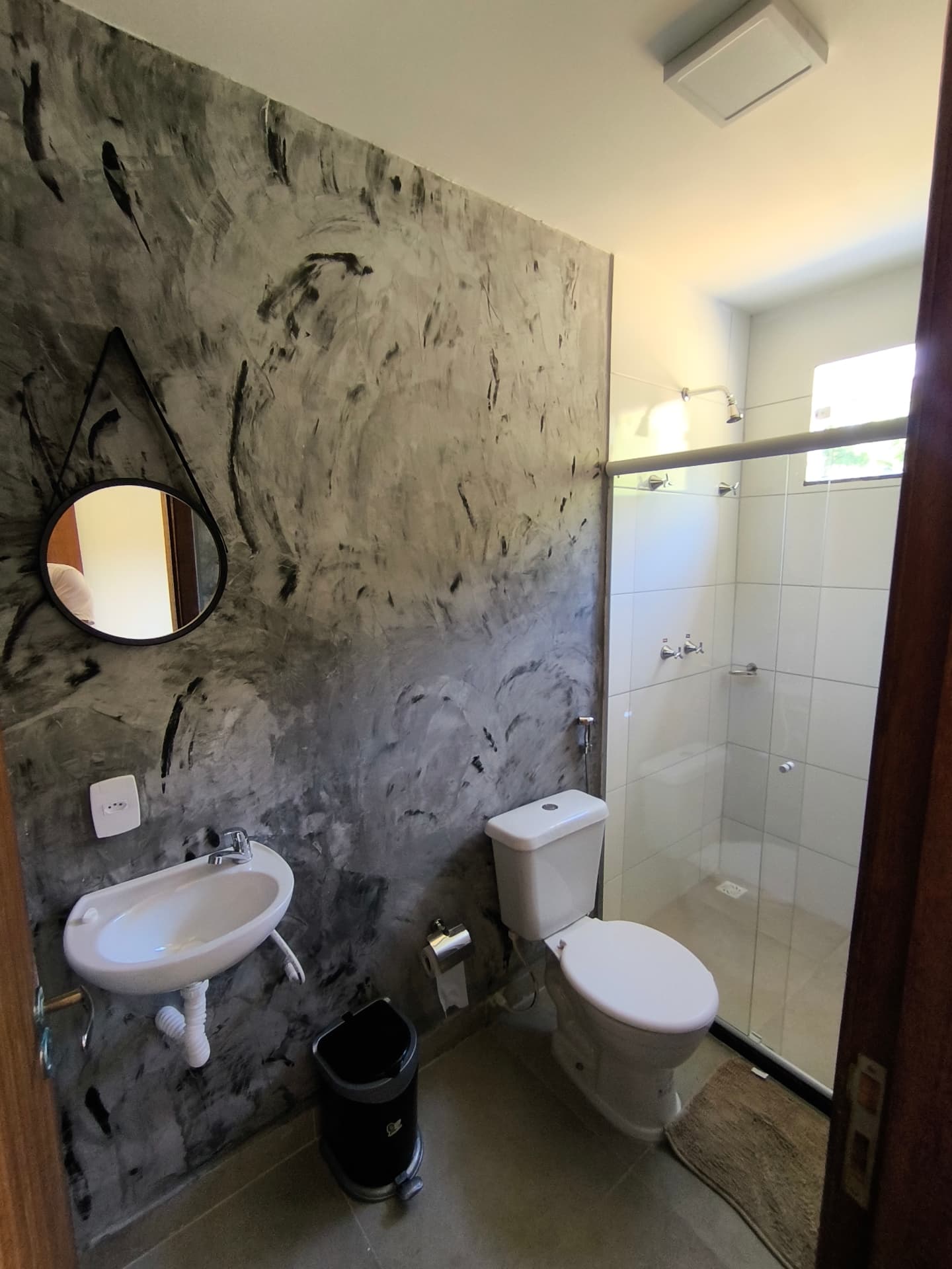 Banheiro da suíte com box e acabamento em cimento queimado